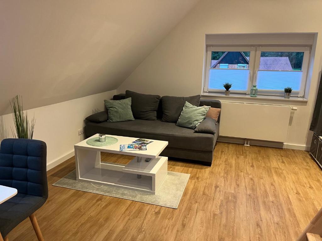Wohnbereich mit Sofa, Couchtisch und Fenster ins Grüne